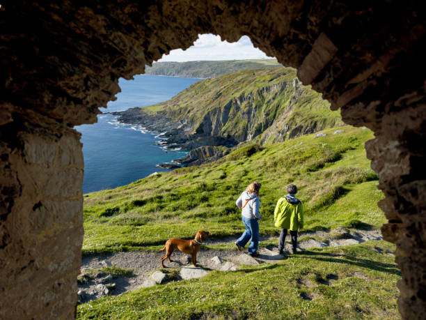 Couple with dog walk along coastal pathway