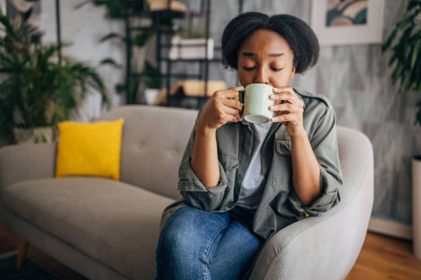 istock Person on couch holding cup in front of face 2154927670