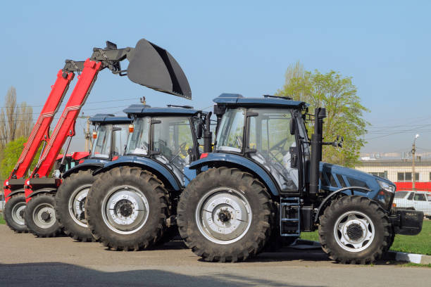Row of agricultural tractors parked on outdoors parking. Side view.