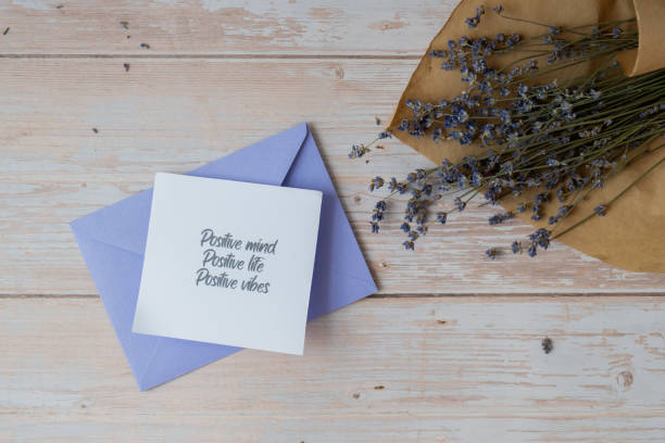 istock Female hands taking paper card note with text POSITIVE MIND LIFE VIBES from violet envelope. Lavender flower. Top view, flat lay. Concept of mental spiritual health self care wellbeing 2154931679