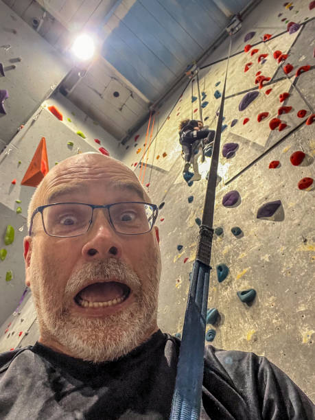 Mature man and daughter doing indoor climbing