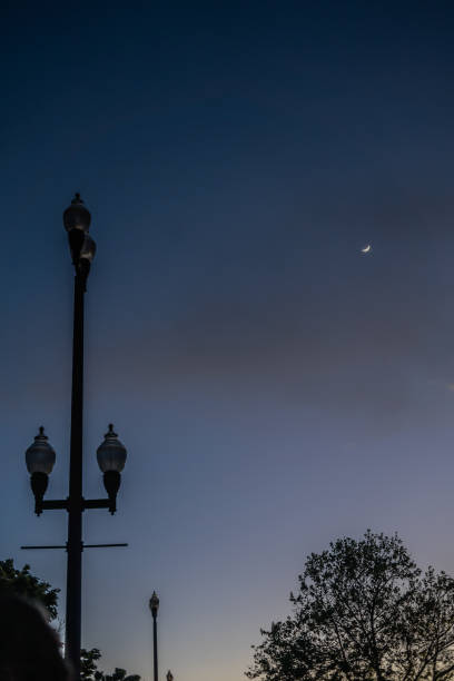 istock Lamp Post and Lights Hazy Sky and Moon Dusk Hour 2154936102