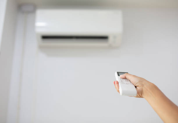istock A woman's hand is pressing a white air conditioner remote. 2154937383