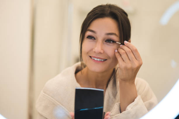 istock Cute dark-haired young woman doing her make up and looking contented 2154941314