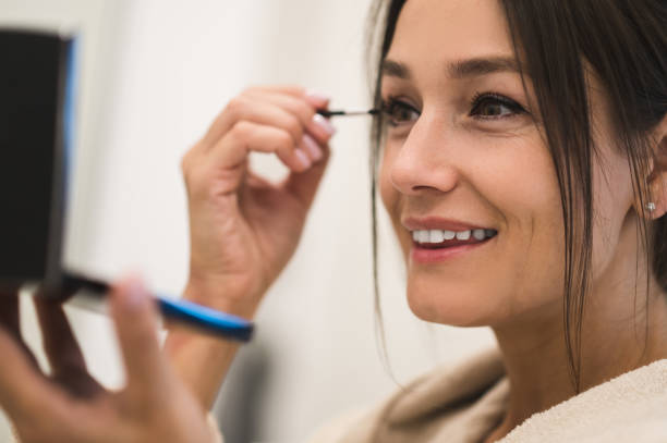 istock Cute dark-haired young woman doing her make up and looking contented 2154941333