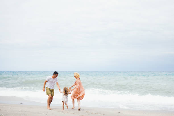 Joyful family enjoying their time on the beach. Parents and child playing by the ocean, creating happy memories together.