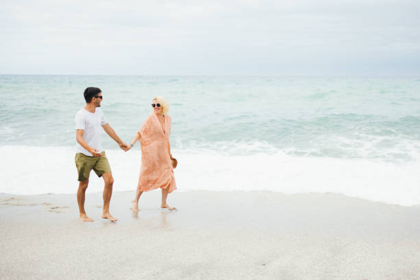 istock Happy Couple Walking on the Beach Holding Hands 2154941505