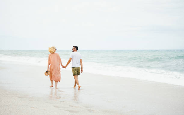istock Couple Holding Hands Walking on the Beach 2154941523