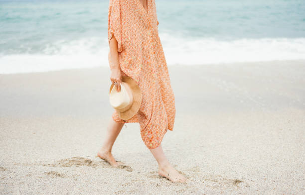 istock Woman Walking on Beach Holding Straw Hat in Summer 2154941542