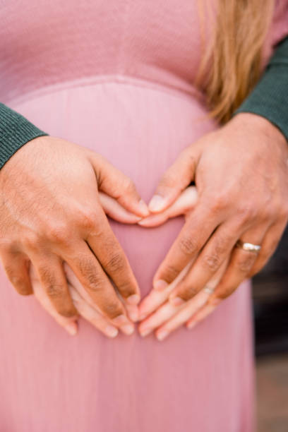 istock An expectant couple make a heart shape with their hands over her growing belly. 2154945671