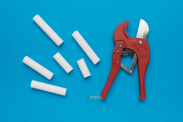 Red Pipe Cutter and White PVC Pipes on Blue Background