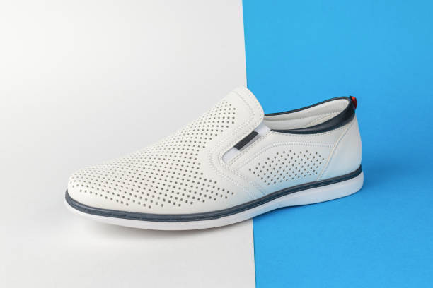 istock White Slip-On Shoe with Perforated Design on Split Blue and White Background 2154946849