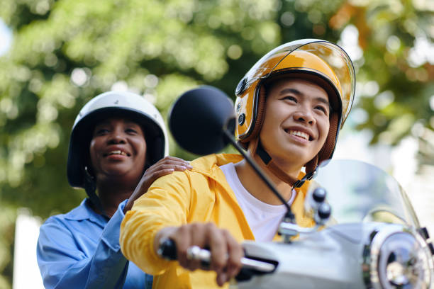 Motorbike Taxi Riding in City Smiling motorbike taxi driver and passenger riding in city vietnamese man taxi motorbike driver stock pictures, royalty-free photos & images