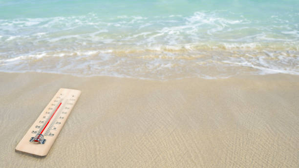 Thermometer with hot temperature on the beach. Environment, global warming, and climate change concept