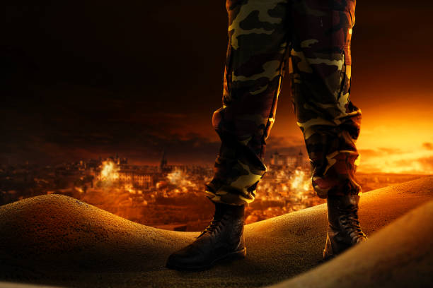 Soldier feet with military boots standing with fire and explosion on war scene background