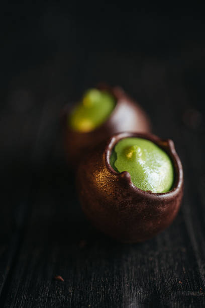Two chocolate candies with green pistachio filling inside at black background