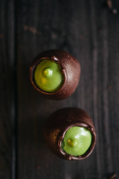 Two chocolate candies with green pistachio filling inside at black background