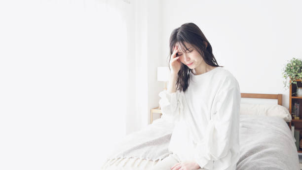 a woman suffering from a headache - 不安 日本人 ストックフォトと画像