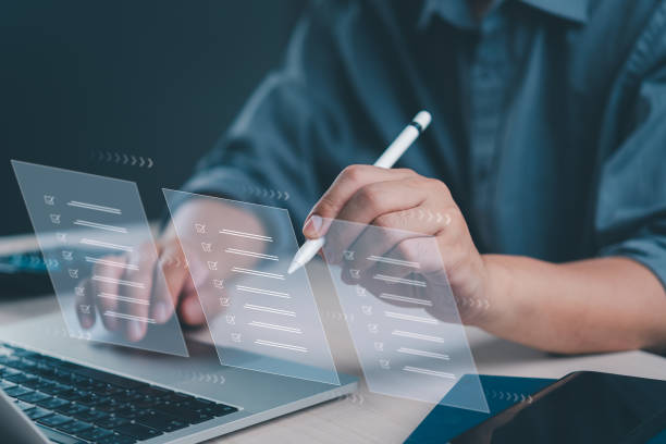 istock Close-up of hands using a futuristic interface for task management, and digital checklist satisfaction on a laptop. 2154958755