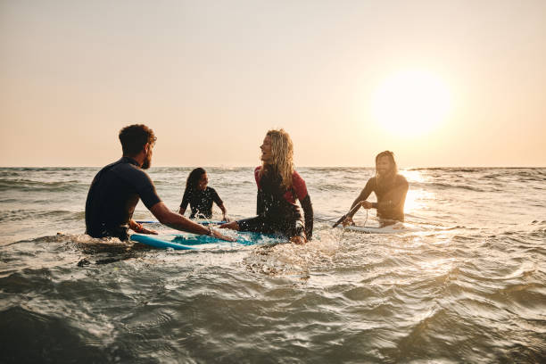 istock Cheerful surfers having fun while talking in sea at sunset. 2154959941