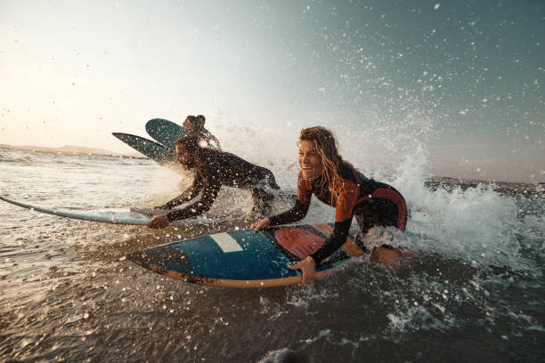 Group of carefree friends having fun while rushing into sea for surfing. Copy space.