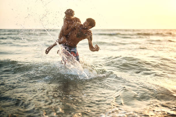 istock Cheerful couple having fun while splashing and piggybacking at sea. 2154960776