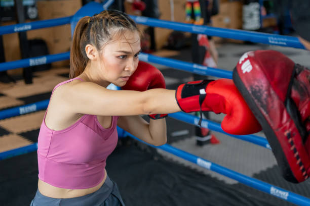 istock Young intense woman practicing boxing with her trainer during her morning exercise at a muaythai gym 2154963156