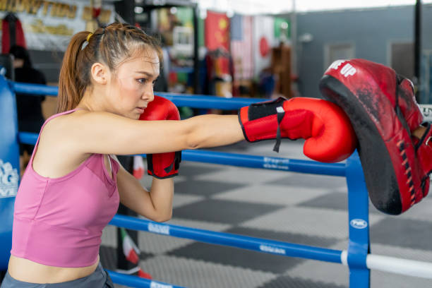 istock Young intense woman practicing boxing with her trainer during her morning exercise at a muaythai gym 2154963179