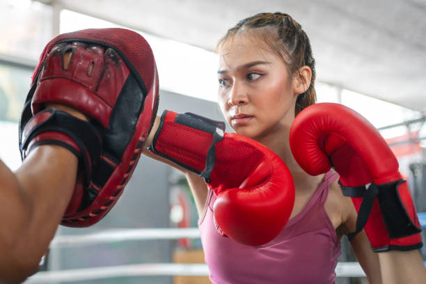 istock Young intense woman practicing boxing with her trainer during her morning exercise at a muaythai gym 2154963183