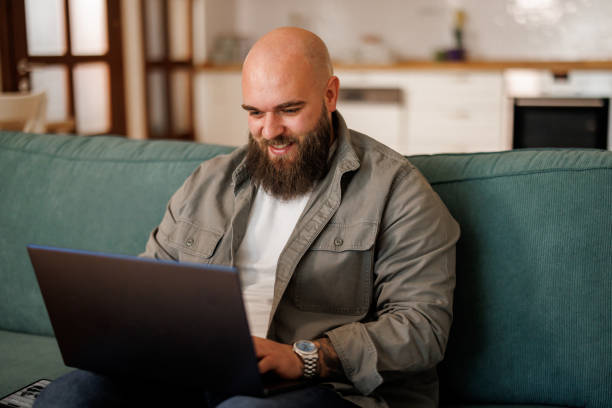 istock Young man using laptop white sitting on cozy sofa at home 2154963209
