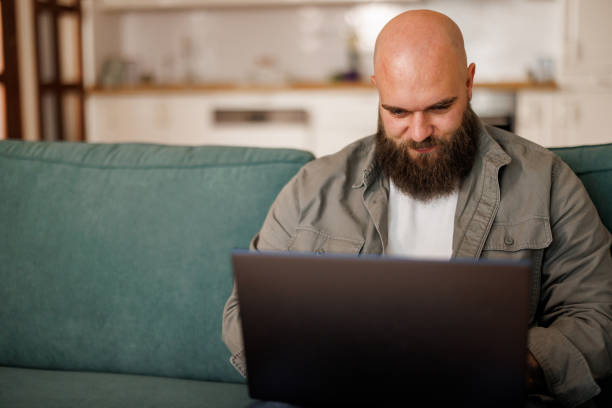 istock Young man using laptop white sitting on cozy sofa at home 2154963778