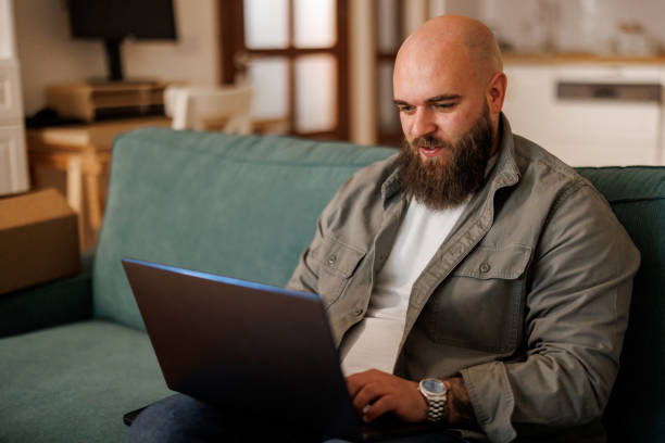 istock Young man using laptop white sitting on cozy sofa at home 2154963826