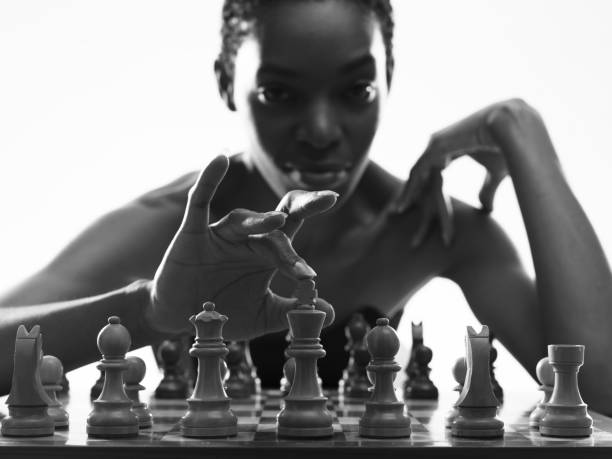 Sensual woman playing chess and looking at camera, she is touching the king, chess game and challenge concept