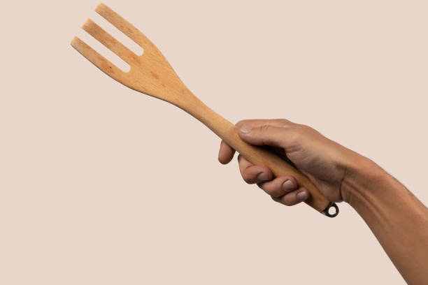 istock Hand holding wooden cooking fork on beige background 2154967048