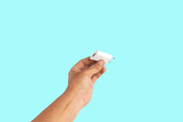 istock Black male hand holding a USB charger plug isolated on green background 2154967080