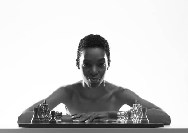 Charming woman playing chess and looking at camera