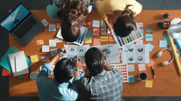 istock Top view of skilled designer holding logo while discussing with team. Symposium. 2154967293