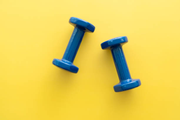 Directly above view of a pair of dumbbells against a yellow background.