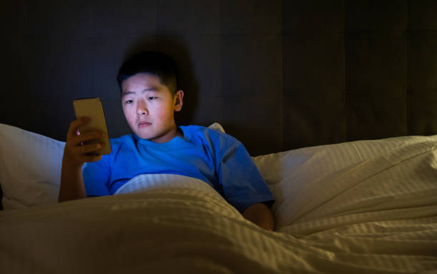 istock Teenage boys using mobile phone in bed 2154967583