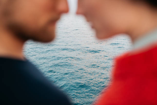 Blurred image of a couple facing each other closely with the focus on the ocean in the background, creating a soft and intimate ambiance.