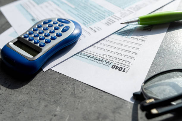 Tax season preparation with tax forms, calculator app, sticky note, and pencil