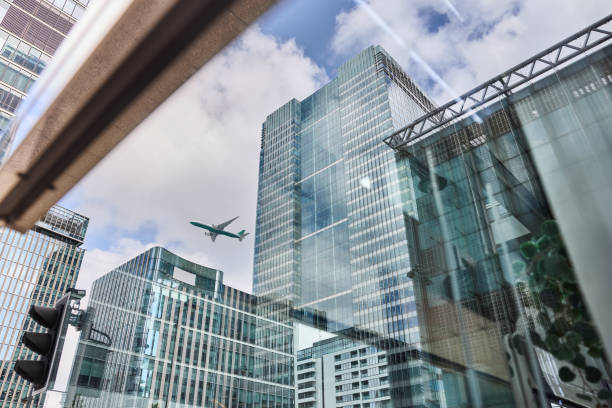 A plane flies over skyscrapers in London photographed during the day