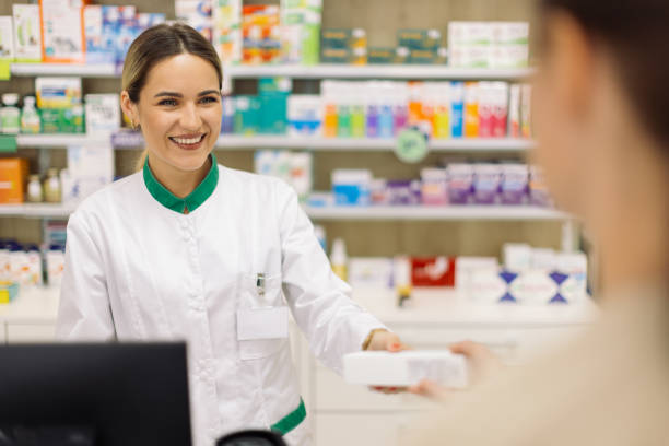istock Young woman pharmacist at her workplace talking with customer 2154970568