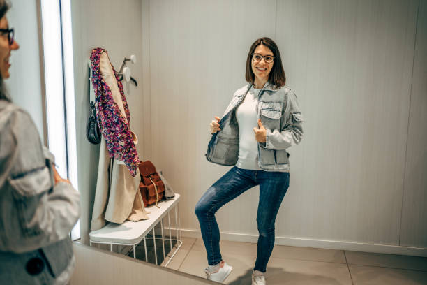 Young cheerful woman trying a jacket in a fitting room