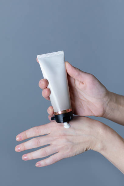istock Woman hands holding hand cream on grey background 2154972578
