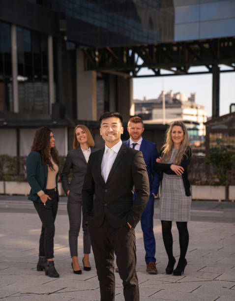 istock happy asian executive smiling with employees behind 2154973713