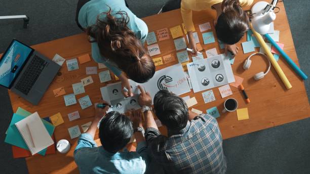 istock Top view of skilled designer holding logo while discussing with team. Symposium. 2154976332