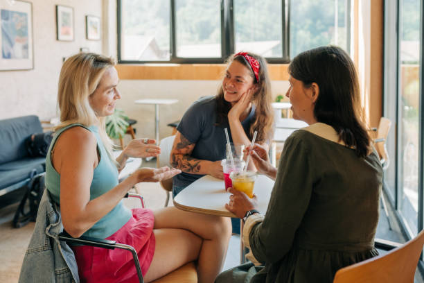 istock Three girlfriends are sitting in a cafe in the summer, chatting and drinking cool drinks. 2154979131