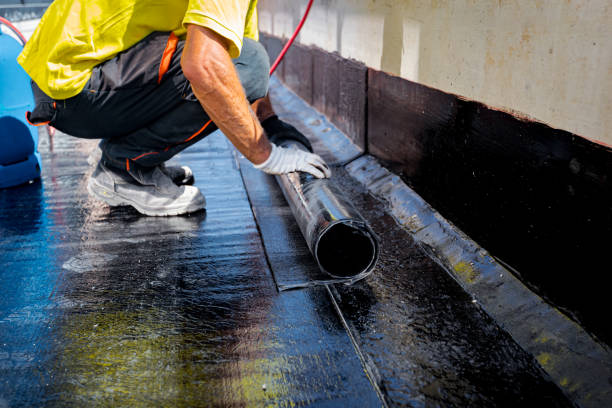istock Worker unroll foil with bitumen waterproofing installation over concrete 2154981535