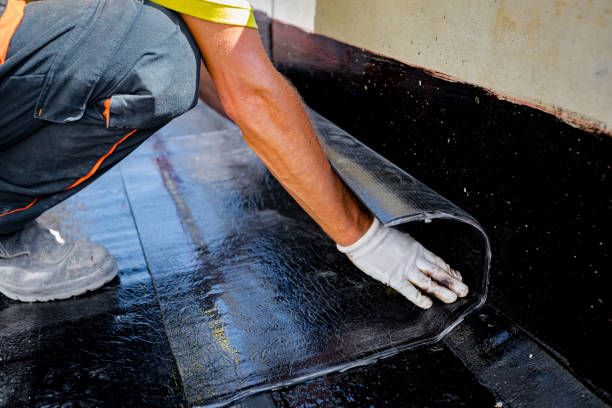 istock Worker unroll foil with bitumen waterproofing installation over concrete 2154981616